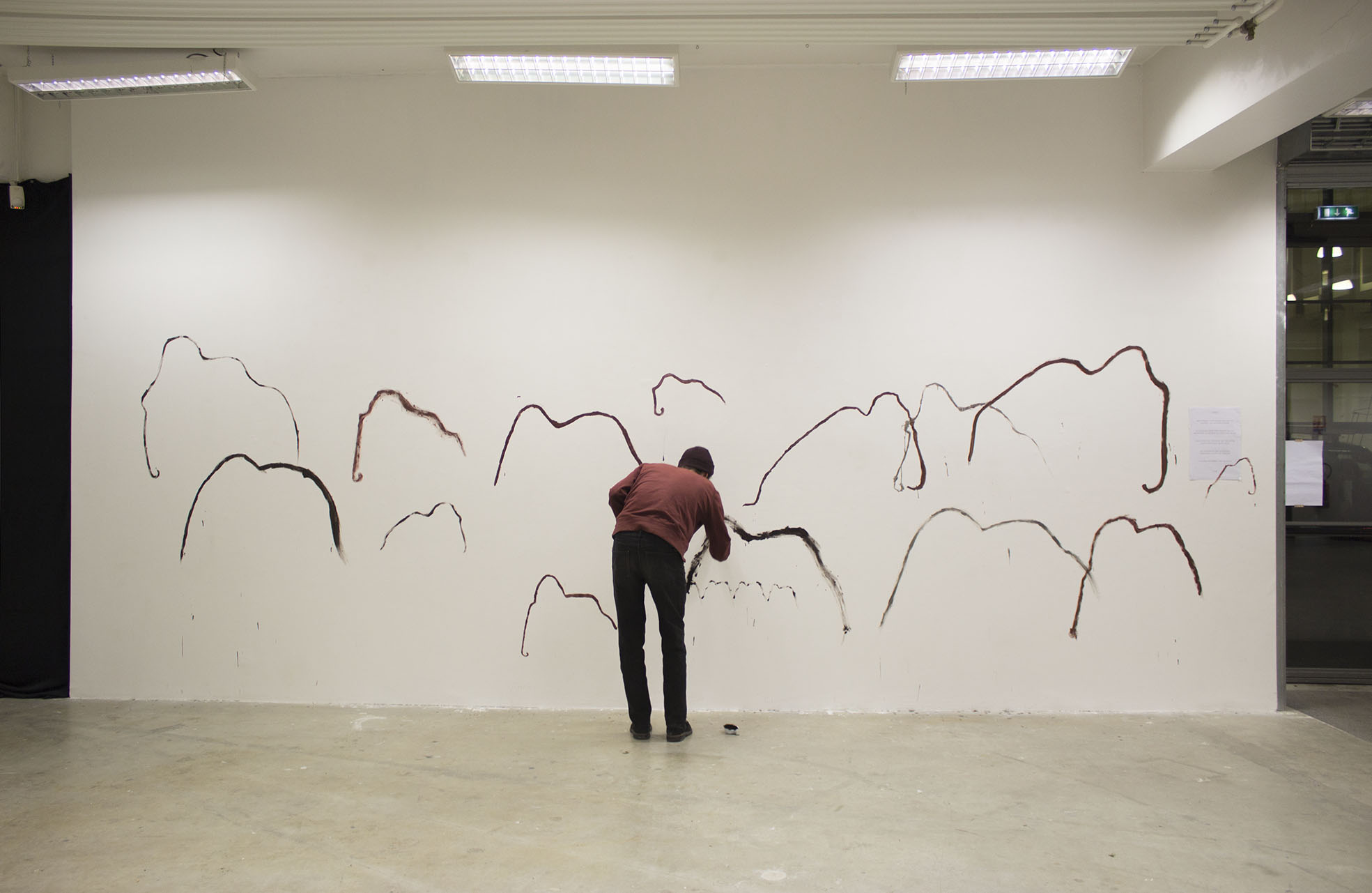 quelqu'un dessine sur le mur. Il y a déjà beaucoup de mammouth sur le mur.